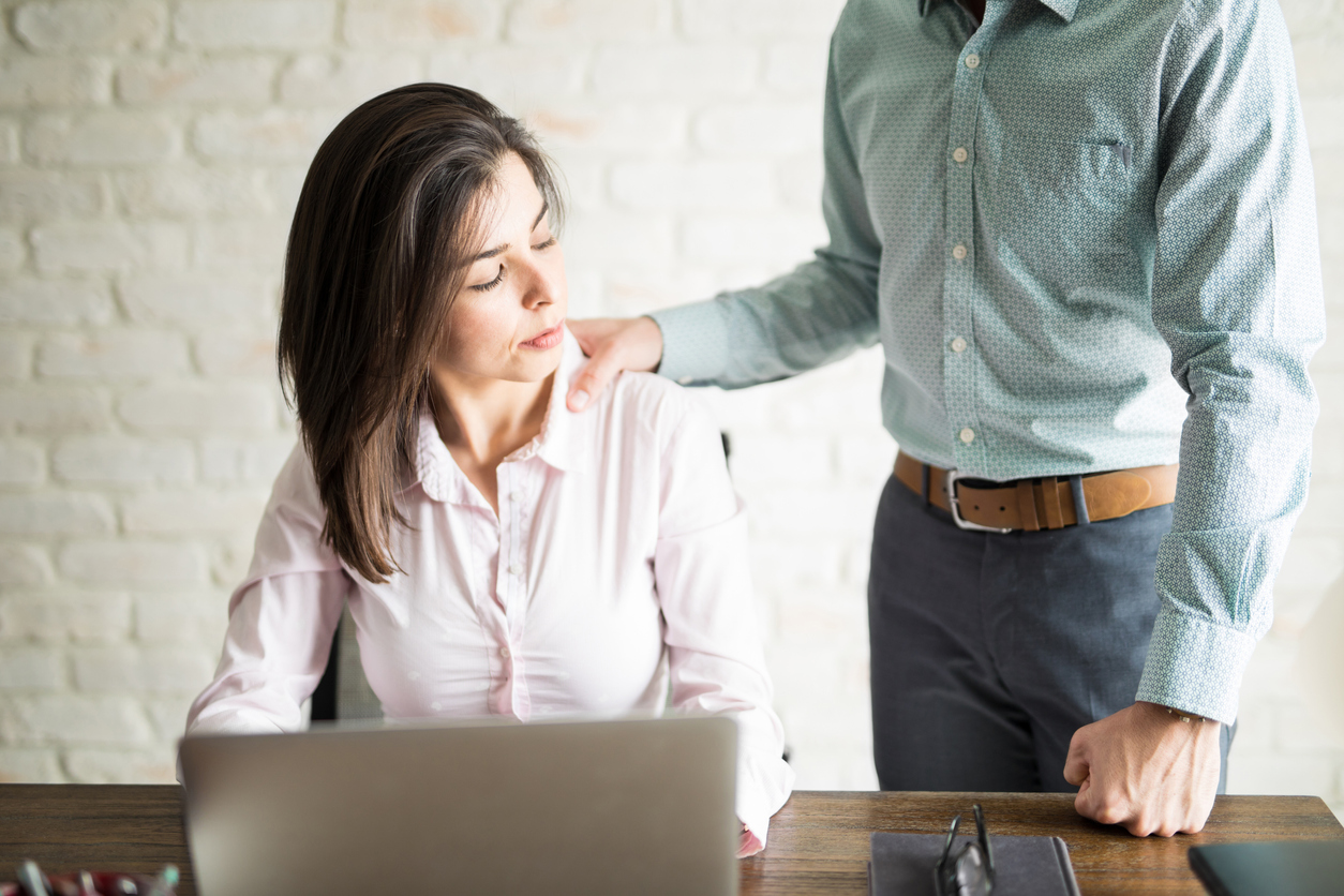Abusive boss harassing a female colleague in the office while she looks uncomfortable and upset