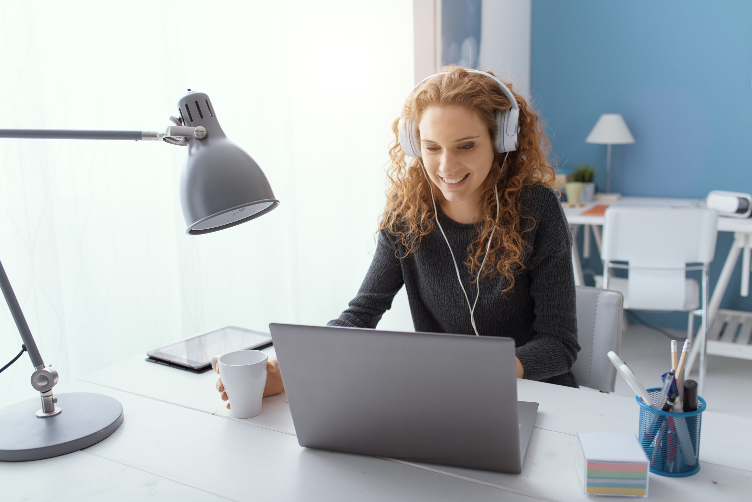 Happy young student girl wearing headphones and watching movies online, leisure and entertainment concept